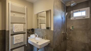 A modern bathroom with a built-in towel rack, a sink, a mirror, and a shower area.