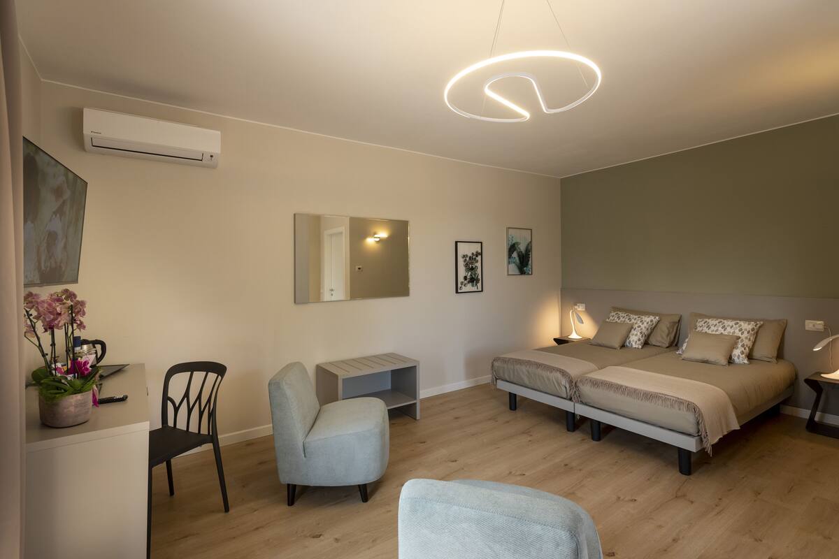 A modern bedroom with a bed, two chairs, a desk, and a small table.