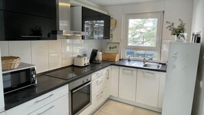 A modern kitchen with white cabinets, a black countertop, a built-in oven, a microwave, and a sink. - Ferienhaus Breisach by Interhome (Breisach)