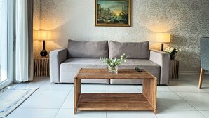 A modern living room with a grey sofa, a wooden coffee table, and two lamps. A framed painting hangs on the wall above the sofa. - Ferienhaus Breisach by Interhome (Breisach)