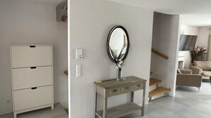 A modern living room with a white cabinet, a console table with a mirror, and a staircase leading to another room. - Ferienhaus Breisach by Interhome (Breisach)