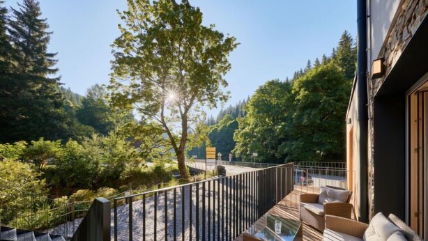 A wooden deck with outdoor seating, surrounded by trees and a stone pathway. - Serene Glow Nook & Terrace by Interhome (Pec pod Snezkou)