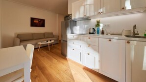 A modern kitchen with white cabinets, a stainless steel refrigerator, and a small dining area with a white table and chairs. - Serene Glow Nook & Terrace by Interhome (Pec pod Snezkou)