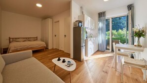 A modern room with a bed, a small kitchenette, a dining area, and a large window with a view of greenery. - Serene Glow Nook & Terrace by Interhome (Pec pod Snezkou)