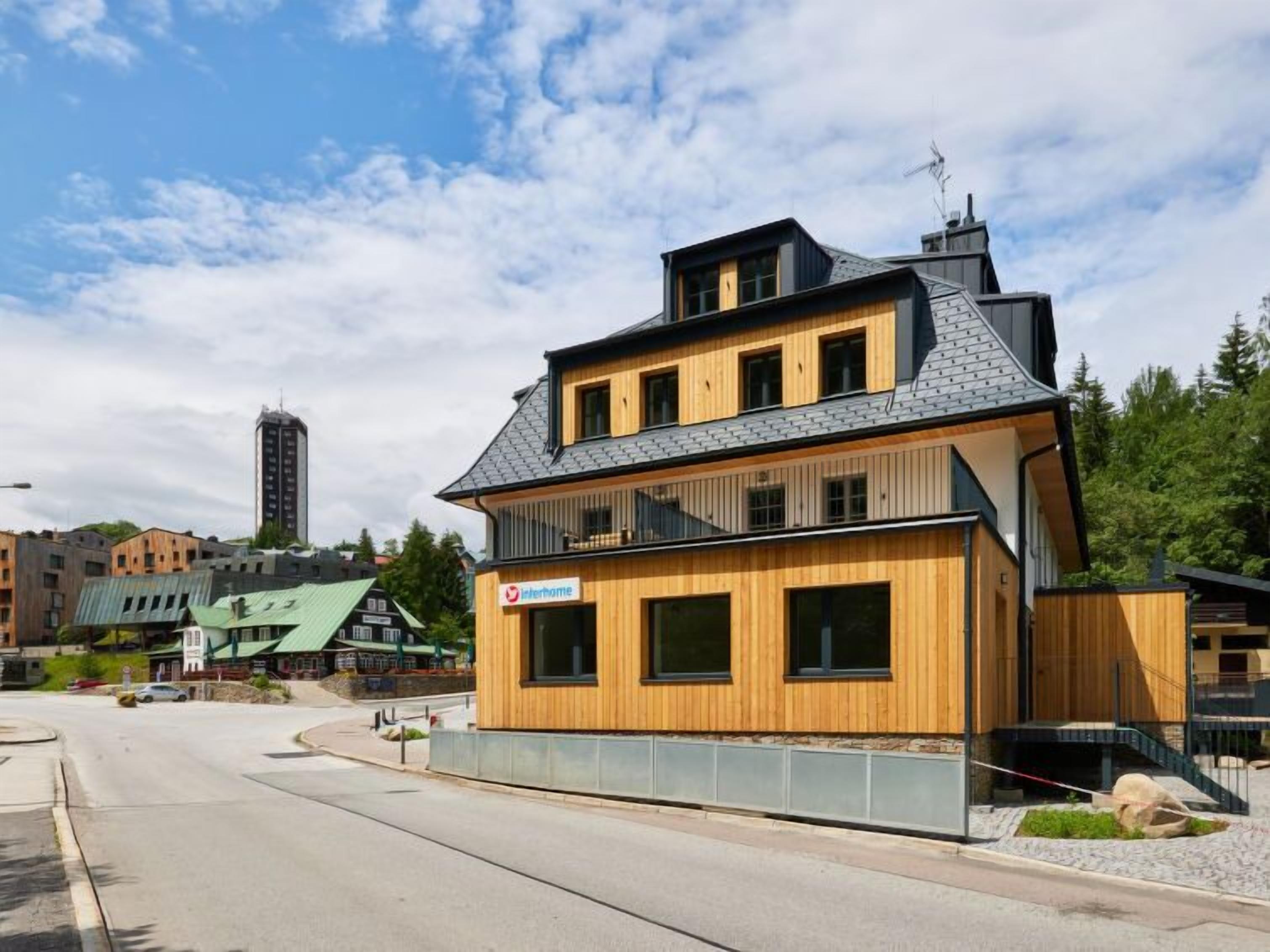 En modern tvåvåningsbyggnad med en träfasad och en skylt med texten ”Interhome”.