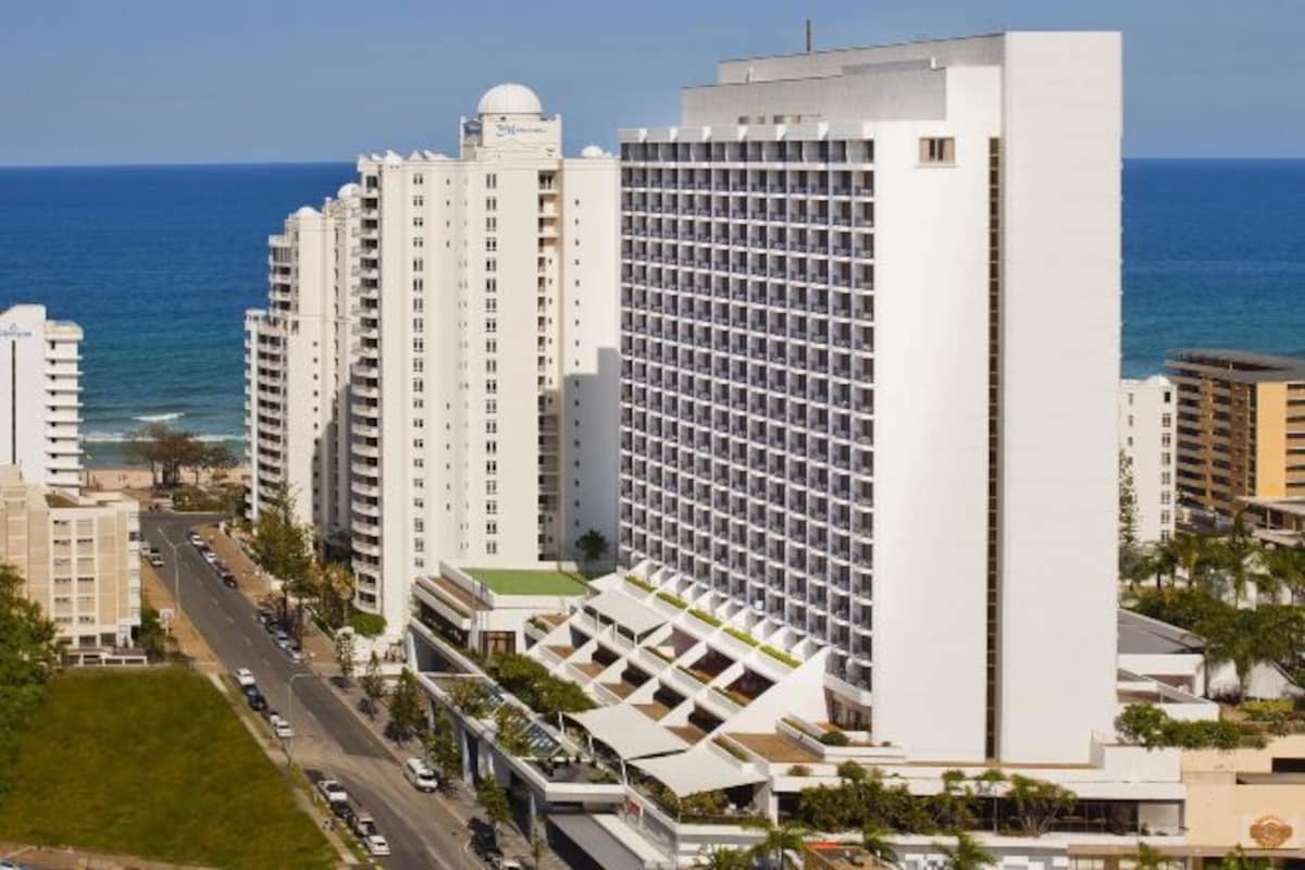 Un hôtel de grande hauteur, avec de nombreux étages, une tour centrale imposante et une vue sur l’océan.
