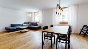 Una sala de estar moderna con un sofá, una mesa de comedor con sillas y una lámpara.
