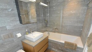 Ein modernes Badezimmer mit einer Duschkabine, einer freistehenden Badewanne, einem Holzbadezimmermöbel und einer Toilette.