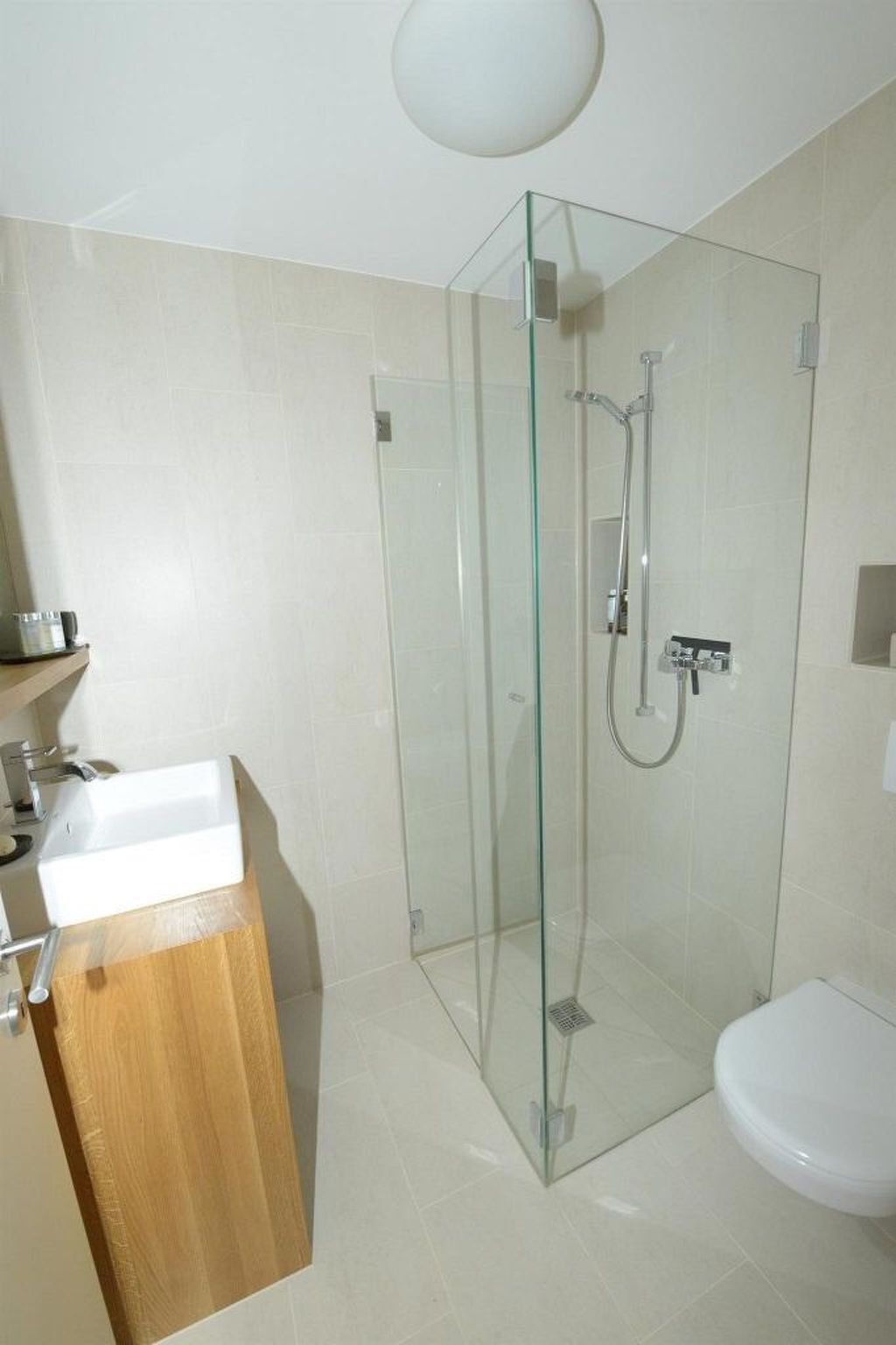 A modern bathroom with a glass-enclosed shower, a wooden vanity, and a white sink.