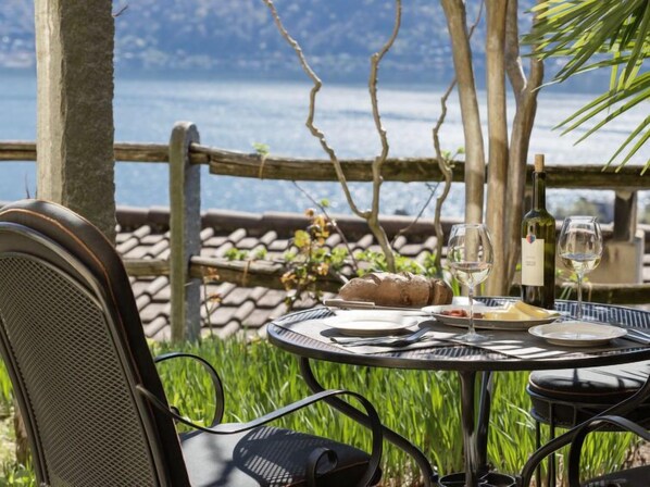 Une table dressée en plein air, avec vue sur la mer, une bouteille de vin et une miche de pain.