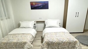 Una habitación con dos camas, un armario y un cuadro en la pared.