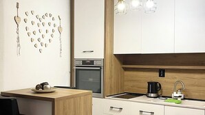 Una cocina moderna con armarios de madera, horno empotrado, cafetera y una zona de bar con taburetes.