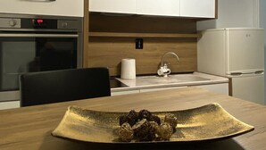 Una cocina moderna con armarios blancos, encimera de madera, horno empotrado, lavamanos y una lámpara colgante.