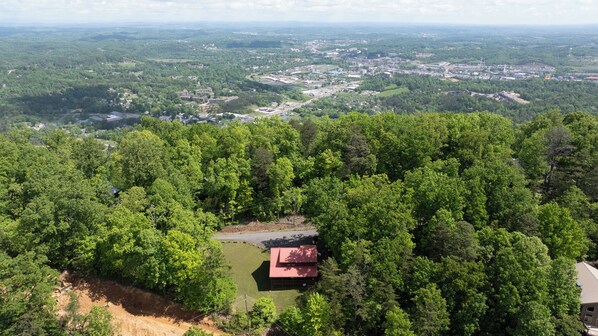 An aerial view of a forested area with a small building with a red roof, surrounded by dense trees. - Convenient Pigeon Forge Cabin-Two Bedroom Pool Table Internet- (Pigeon Forge)