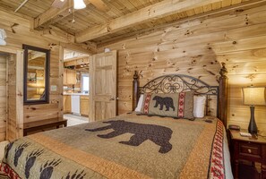 A wooden cabin-style room with a bed featuring a bear quilt, a wooden headboard, and a nightstand with a lamp. - Convenient Pigeon Forge Cabin-Two Bedroom Pool Table Internet- (Pigeon Forge)