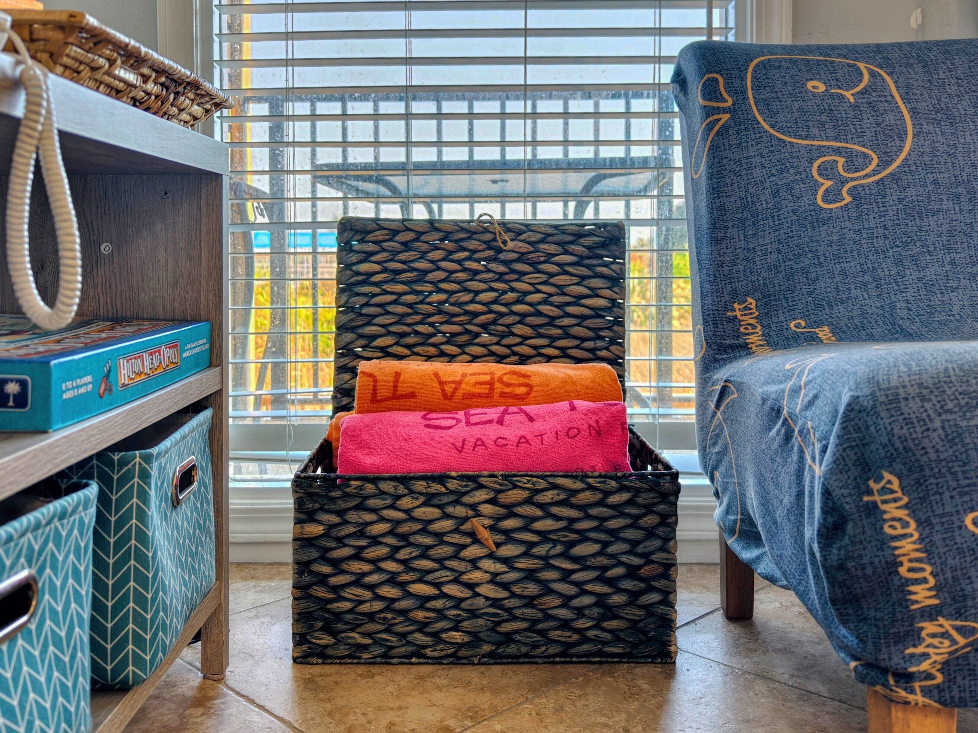 A room with a blue chair, a wicker basket, a box of games, and a storage unit with patterned fabric.