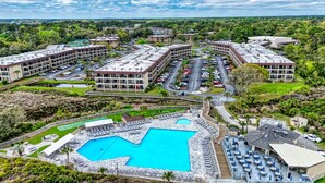 A resort with multiple buildings, a large swimming pool, and outdoor seating areas. - Ocean Front Condo with Resort Amenities, Short Walk to Beach (Hilton Head Island)