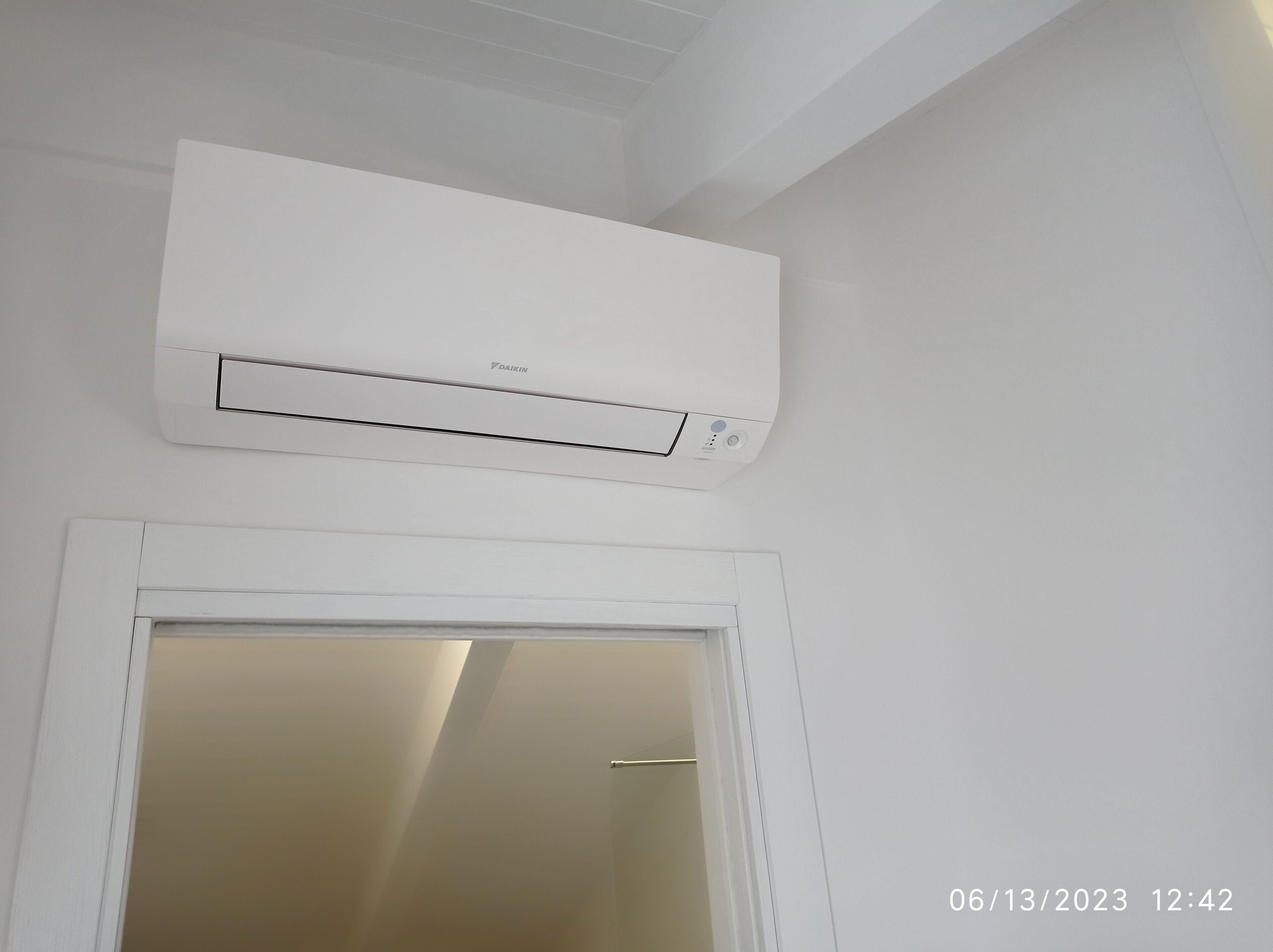 Un condizionatore d'aria bianco montato sopra una porta bianca.