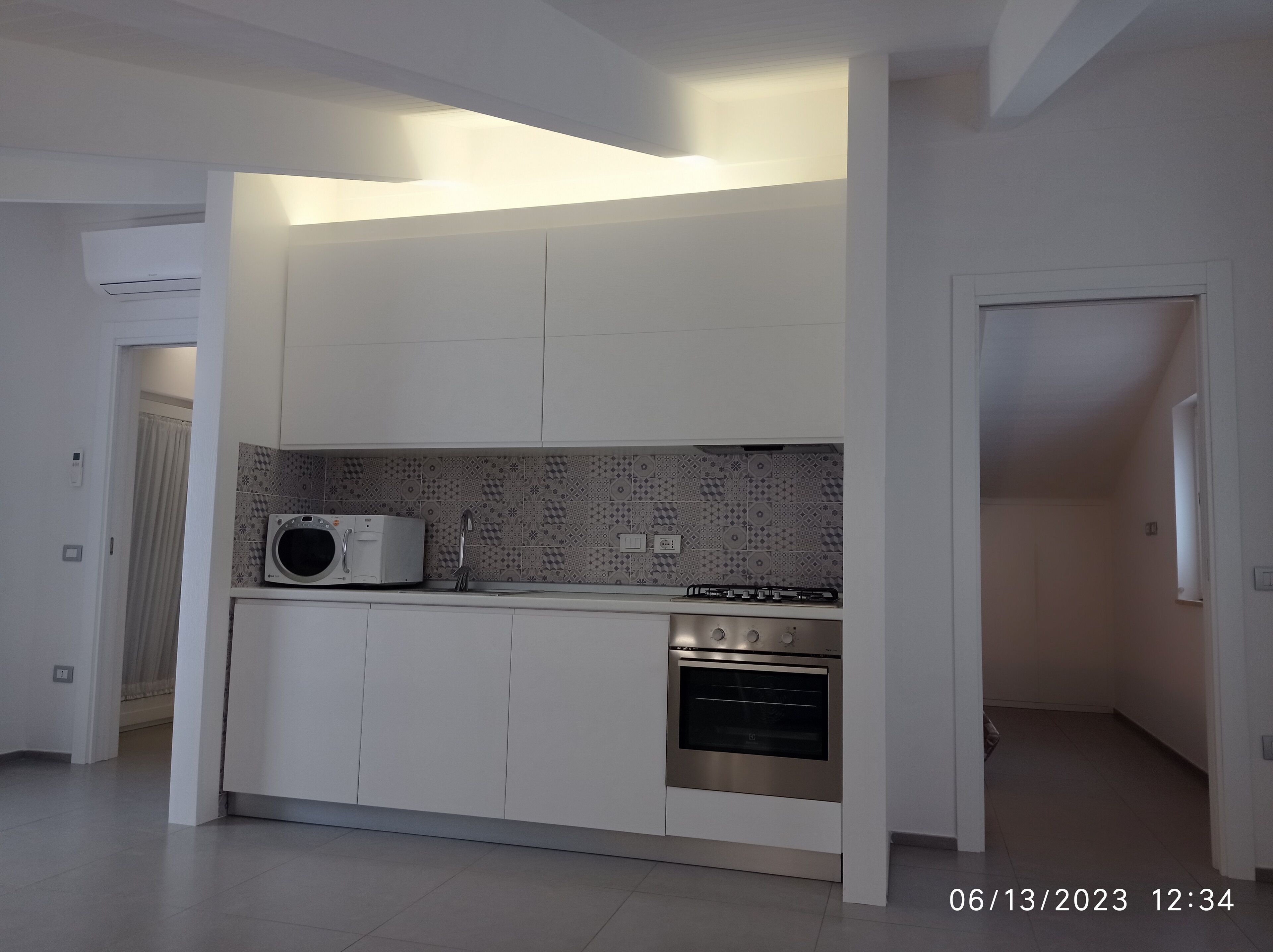 Eine moderne Küche mit weißen Schränken, einer Mikrowelle, einem Gasherd und einem Backofen.