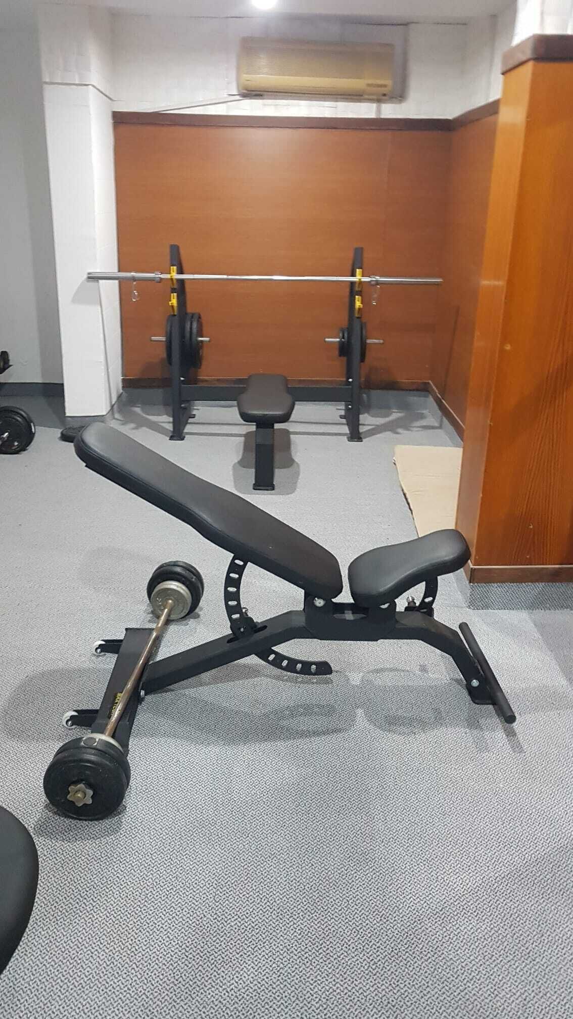 Een sportschool met een bankdrukapparaat, een power rack en een halter.