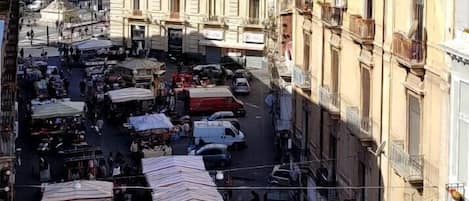 A bustling street market with vendors and stalls, surrounded by historic buildings.