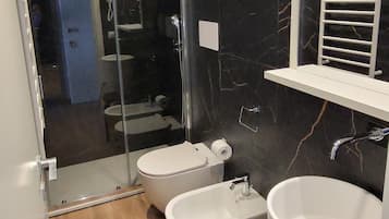 A modern bathroom with a glass shower enclosure, two sinks, and a large bathtub.
