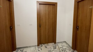 A hallway with three wooden doors, numbered 102, 103, and 104, leading to individual rooms. - B&B CENTRALE (Gela)