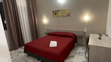 A hotel room with a bed, a desk, and a chair.