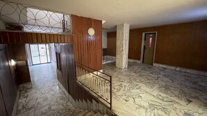 A spacious interior with a marble floor, a wooden staircase, and a metal railing. - B&B CENTRALE (Gela)