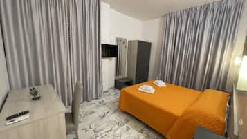 Una habitación de hotel con cama, escritorio, televisor y armario.