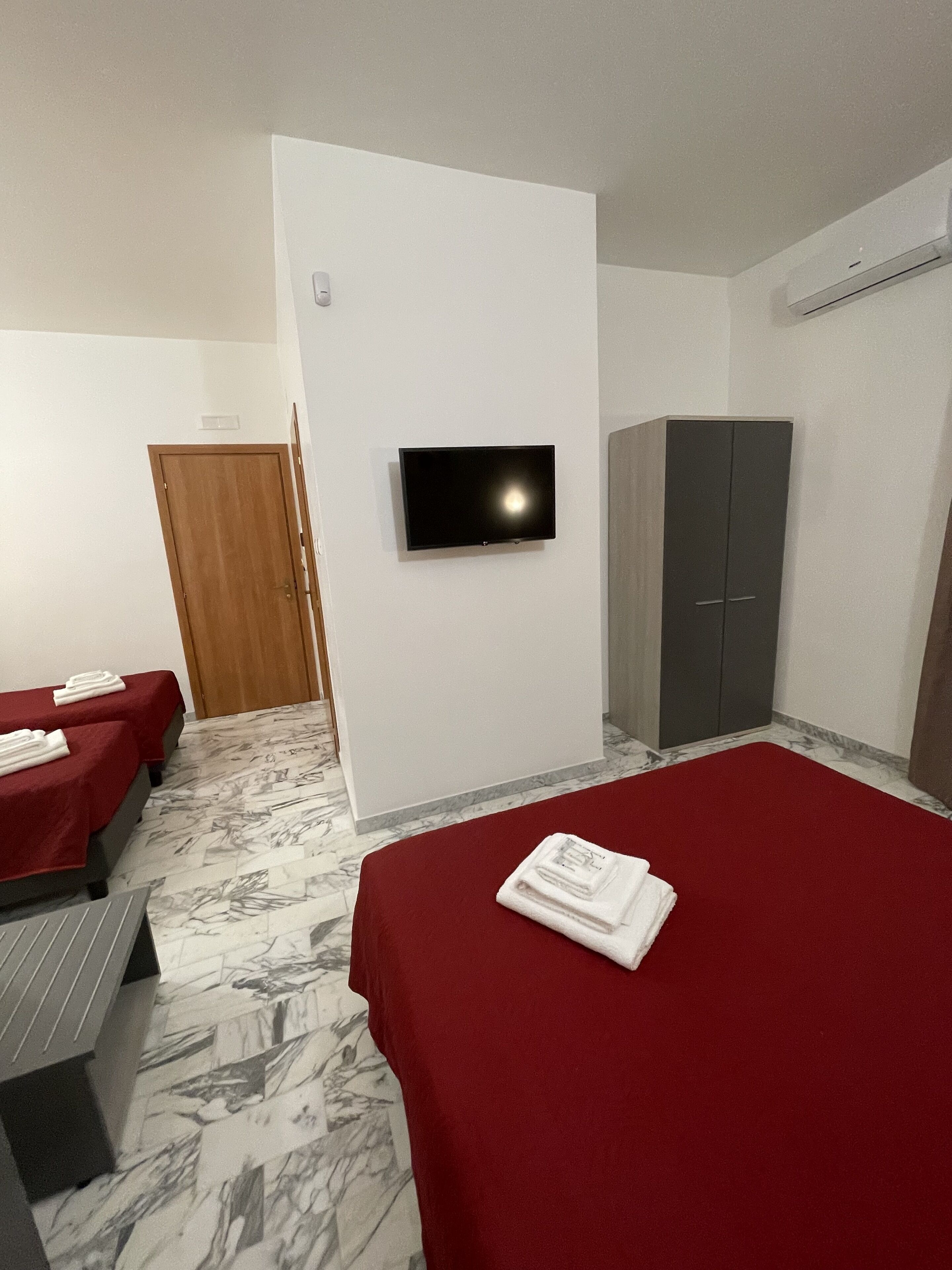 A hotel room with a bed, a TV, a wardrobe, and a massage table.