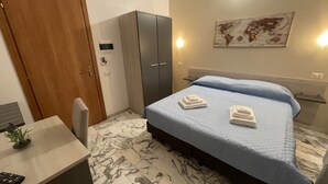 A hotel room with a bed, a desk, a wardrobe, and a world map on the wall. - B&B CENTRALE (Gela)
