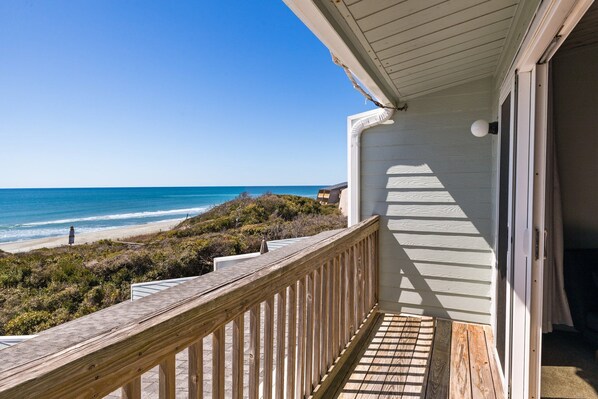 A wooden deck with a view of the beach and ocean.