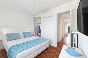 A bedroom with a bed, bedside table, and a view of the hallway.