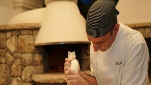 Un chef preparando pizza en una cocina con horno de ladrillo.