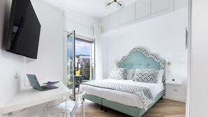 Une chambre à coucher avec un lit, un bureau avec un ordinateur portable, une chaise et un téléviseur fixé au mur.