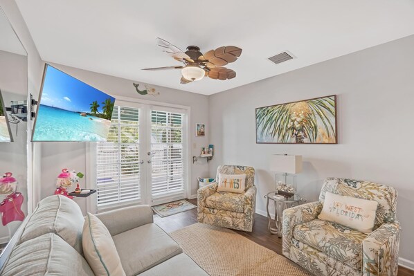 Relax in a spacious living room with a large flat-screen TV, comfortable seating area, and sliding glass door leading to an outdoor space.