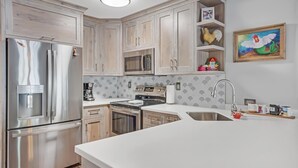 A modern kitchen with stainless steel appliances, wooden cabinets, and a white countertop. - A Fish Bowl at The Truman Annex in Key West (Key West)