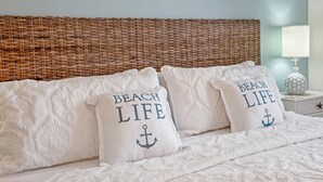 A bed with white bedding and pillows featuring the text "BEACH LIFE" and an anchor design. - A Fish Bowl at The Truman Annex in Key West (Key West)