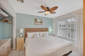 Relax in this inviting bedroom with a large bed, wooden headboard, and a bedside table with a lamp.