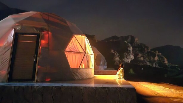 Una tenda a cupola geodetica con un'apertura e una struttura più piccola ad essa collegata, con una tenda.