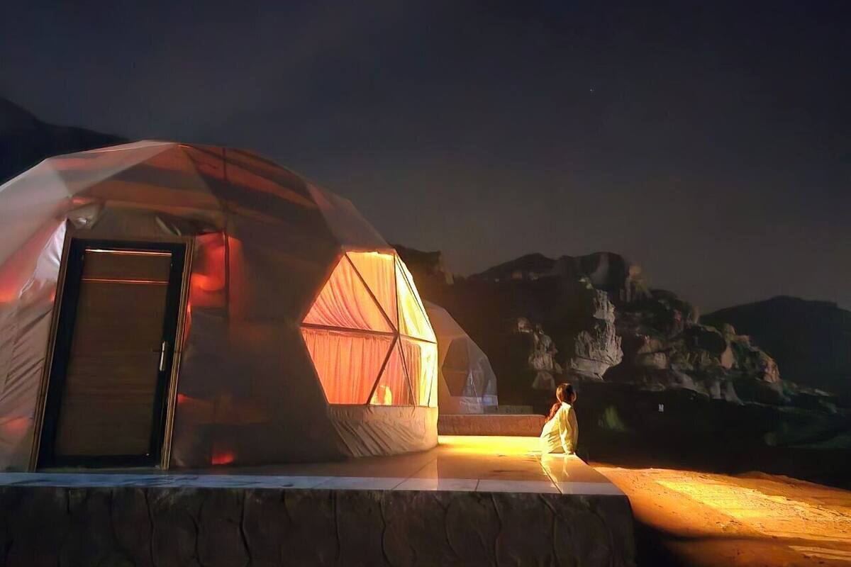 A geodesic dome tent with a door and a smaller attached structure with a curtain.