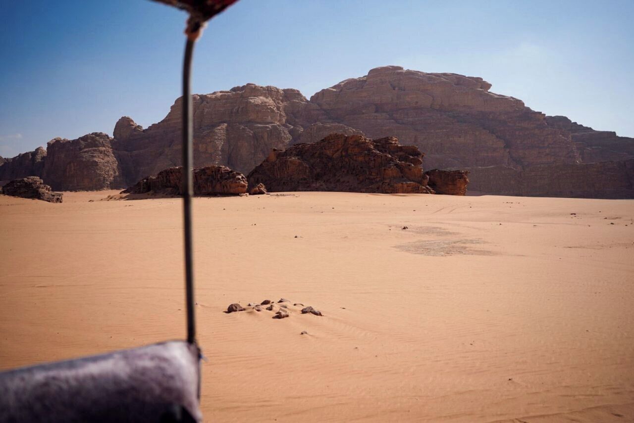A desert landscape with prominent rock formations in the background.