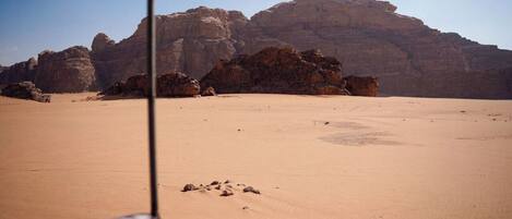 A desert landscape with prominent rock formations in the background.