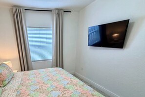 A bedroom with a bed, a television on the wall, and a window with curtains. - 6/6 for 12+ Big Heated Pool w/ Tiki Bar-BBQ-Beach (Hollywood)