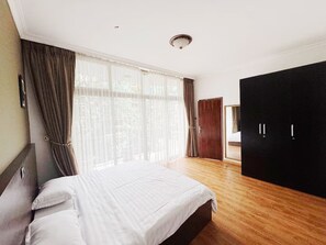 Une chambre à coucher avec un grand lit, une armoire et une porte donnant sur une autre pièce.