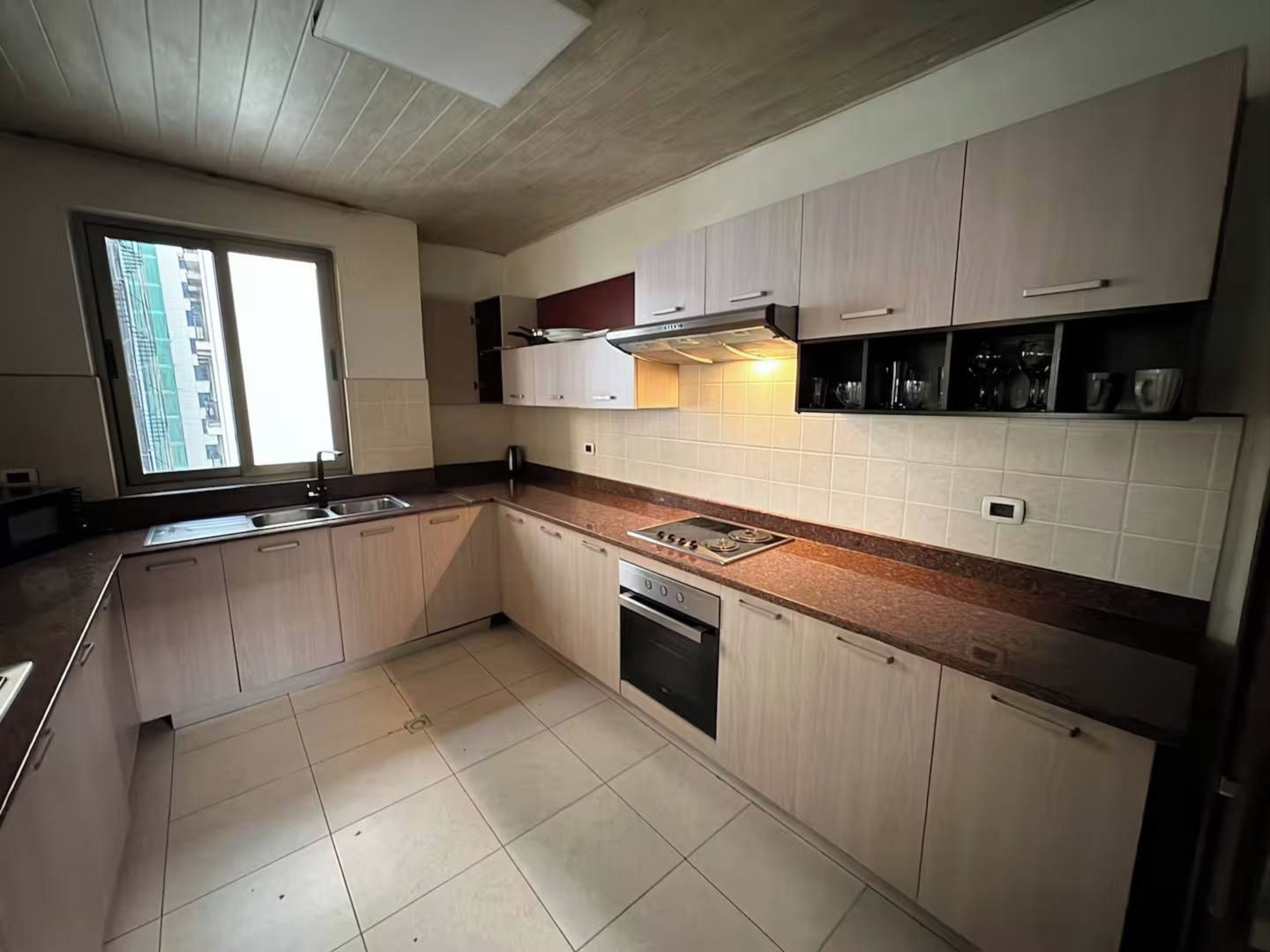Een moderne keuken met lichte houten kastjes, een roestvrijstalen spoelbak en een inbouwoven.
