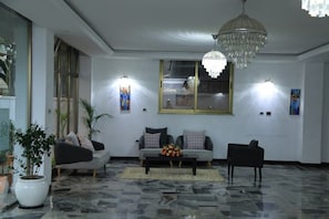 A modern living room with a marble floor, a chandelier, two sofas, a coffee table, and wall-mounted lights.