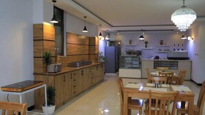 Una cocina moderna con armarios de madera, un comedor con mesas y sillas de madera, e iluminación colgante.