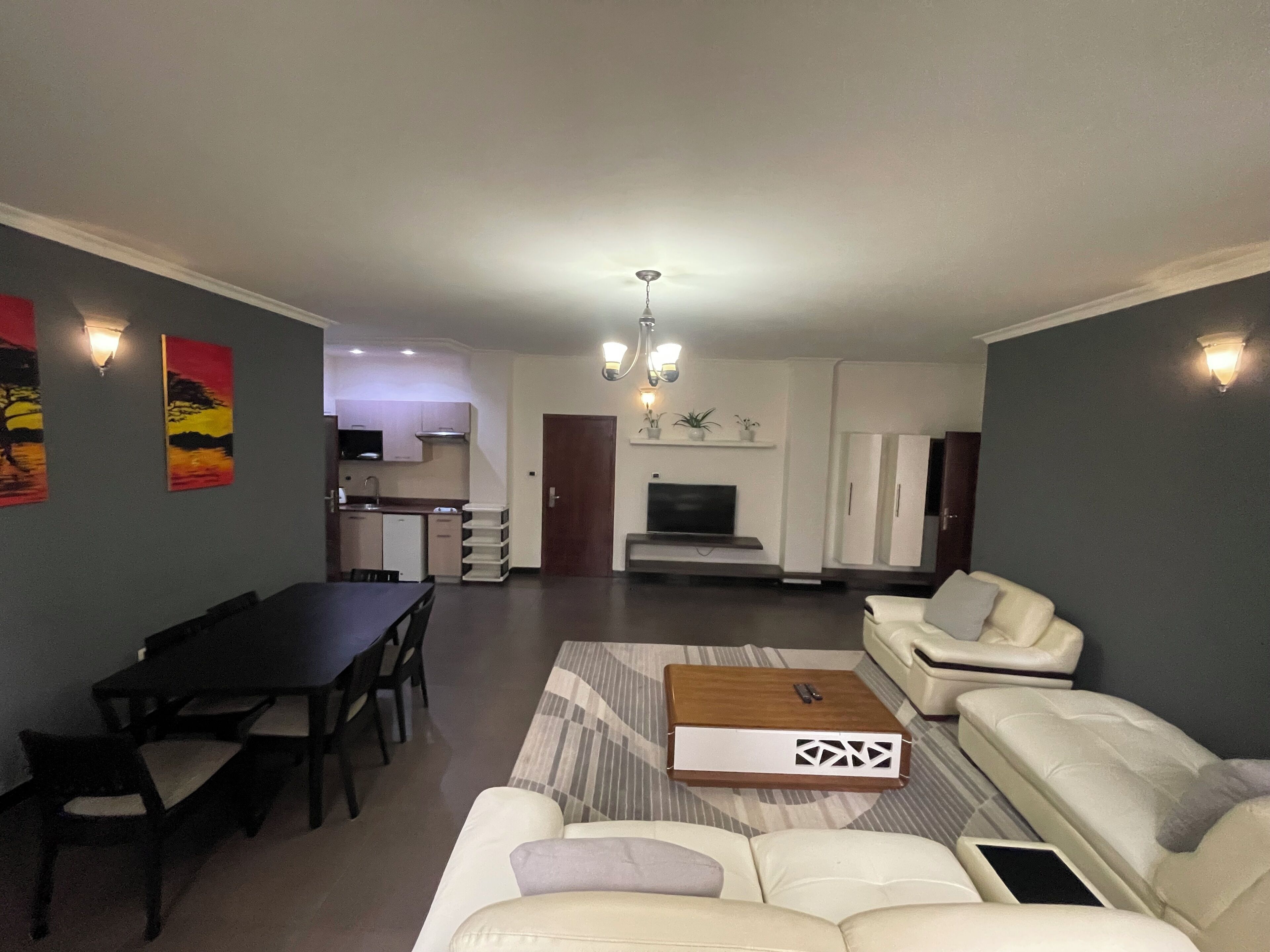 A living room with a sofa, a coffee table, a TV, and a dining area with a table and chairs.